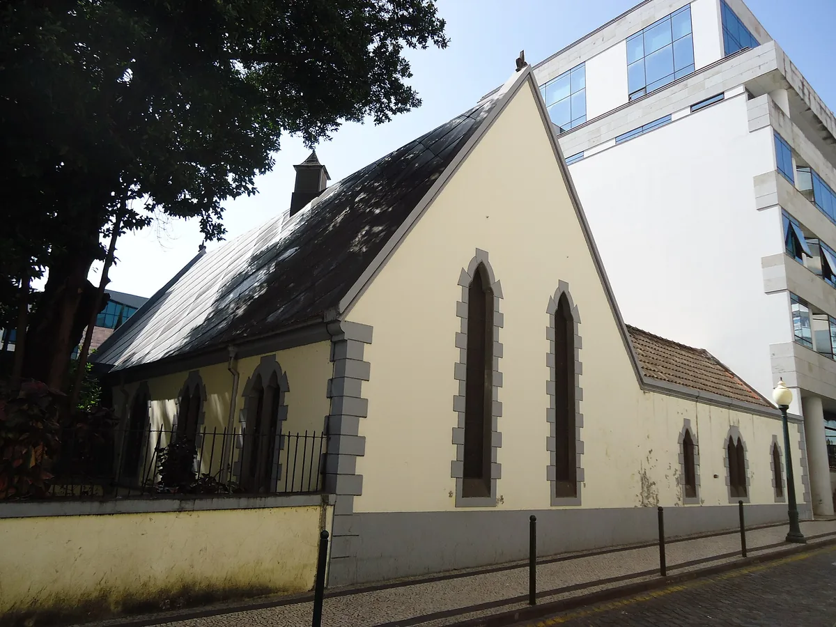 The long side wall of St Andrew's church seen from the street, with pointed windows, a gabled roof and a modern building rising behind